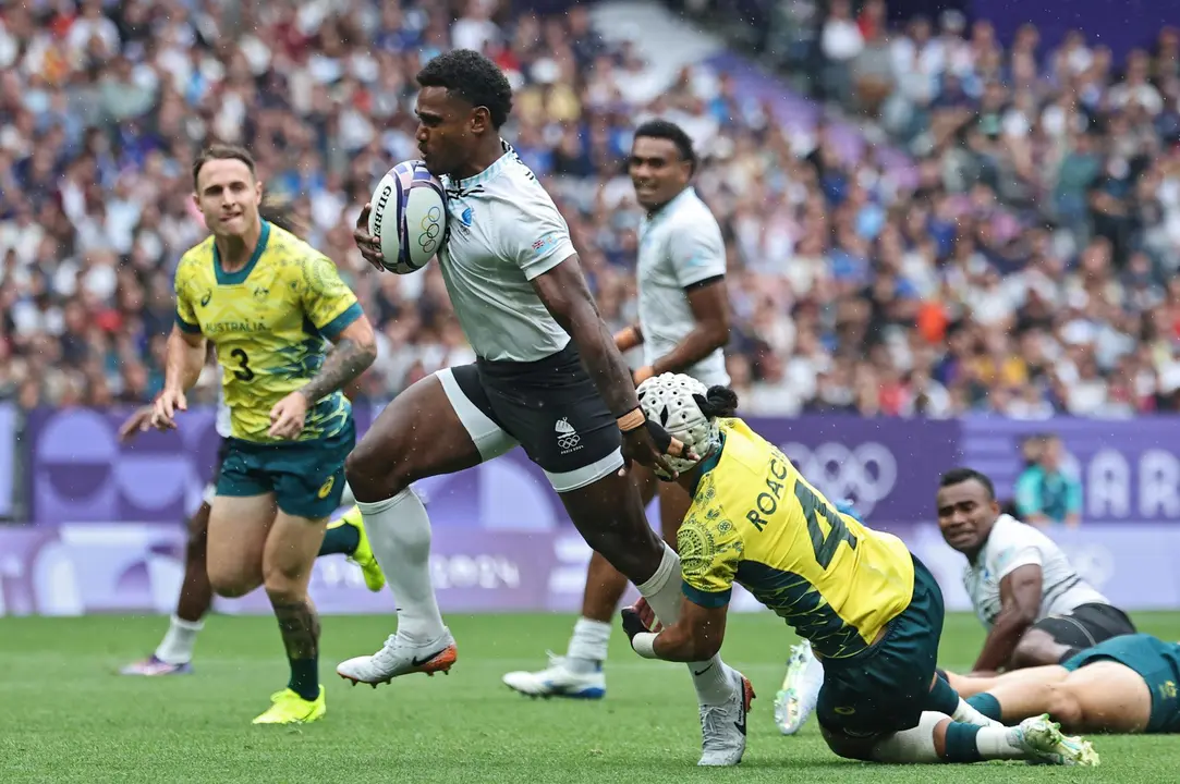 El jugador Jerry Tuwai, de Fiji, deja a tr&aacute;s al australiano durante el partido de semifinales que han jugado Fiji y Australia en el Stade de France en Saint Denis, Francia. EFE/EPA/CHRISTOPHE PETIT TESSON