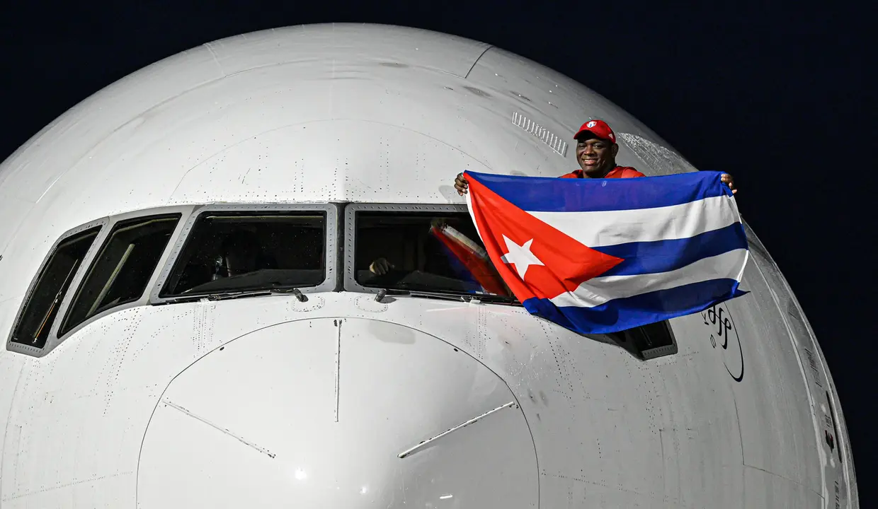 El luchador cubano Mija&iacute;n L&oacute;pez, cinco veces campe&oacute;n ol&iacute;mpico, sostiene una bandera de Cuba en la ventanilla del piloto a su llegada este lunes al aeropuerto Jos&eacute; Mart&iacute; de La Habana. EFE/ AFP /Adalberto Roque/POOL