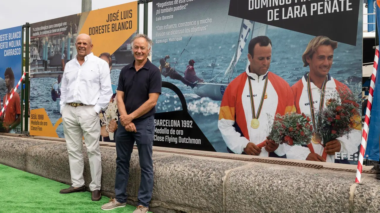 Los regatistas Luis Doreste (d) y Domingo Manrique (i), medallas de oro de vela en los Juegos de Barcelona de 1992 en la clase flying dutchman, posan ante una foto suya de EFE en el mural que el Real Club N&aacute;utico de Gran Canaria ha instalado en la rampa donde embarcan sus tripulaciones para inspirar sus su j&oacute;venes promesas con los logros de sus ol&iacute;mpicos. EFE/Quique Curbelo