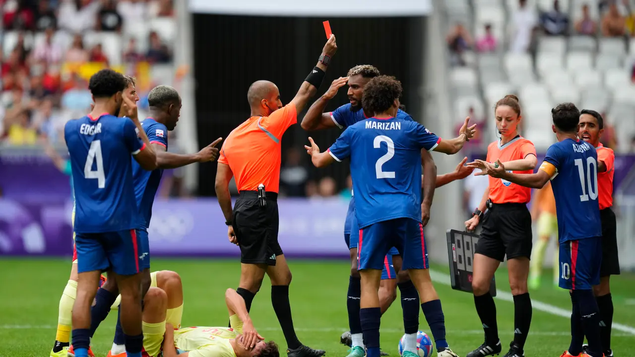 El &aacute;rbitro Adel Al Naqbi (c) le saca la tarjeta roja al dominicano Edison Azcona (d) tras una acci&oacute;n contra Pau Cubars&iacute; (en el suelo) durante el partido del Grupo C de f&uacute;tbol masculino de los Juegos Ol&iacute;mpicos de Par&iacute;s 2024 disputado este s&aacute;bado en el Estadio de Burdeos. EFE/ M. Reino